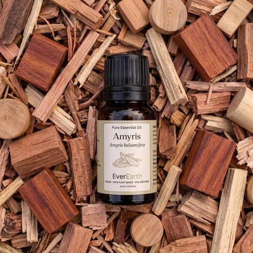 EverEarth Amyris essential oil bottle resting on a bed of amyris wood chips and blocks