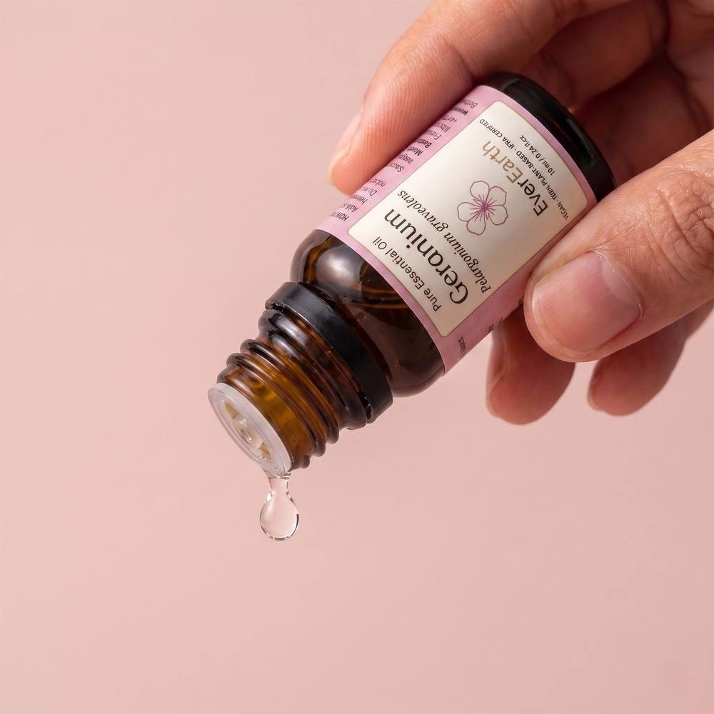 Hand dispensing a drop of EverEarth Geranium essential oil from the amber glass bottle