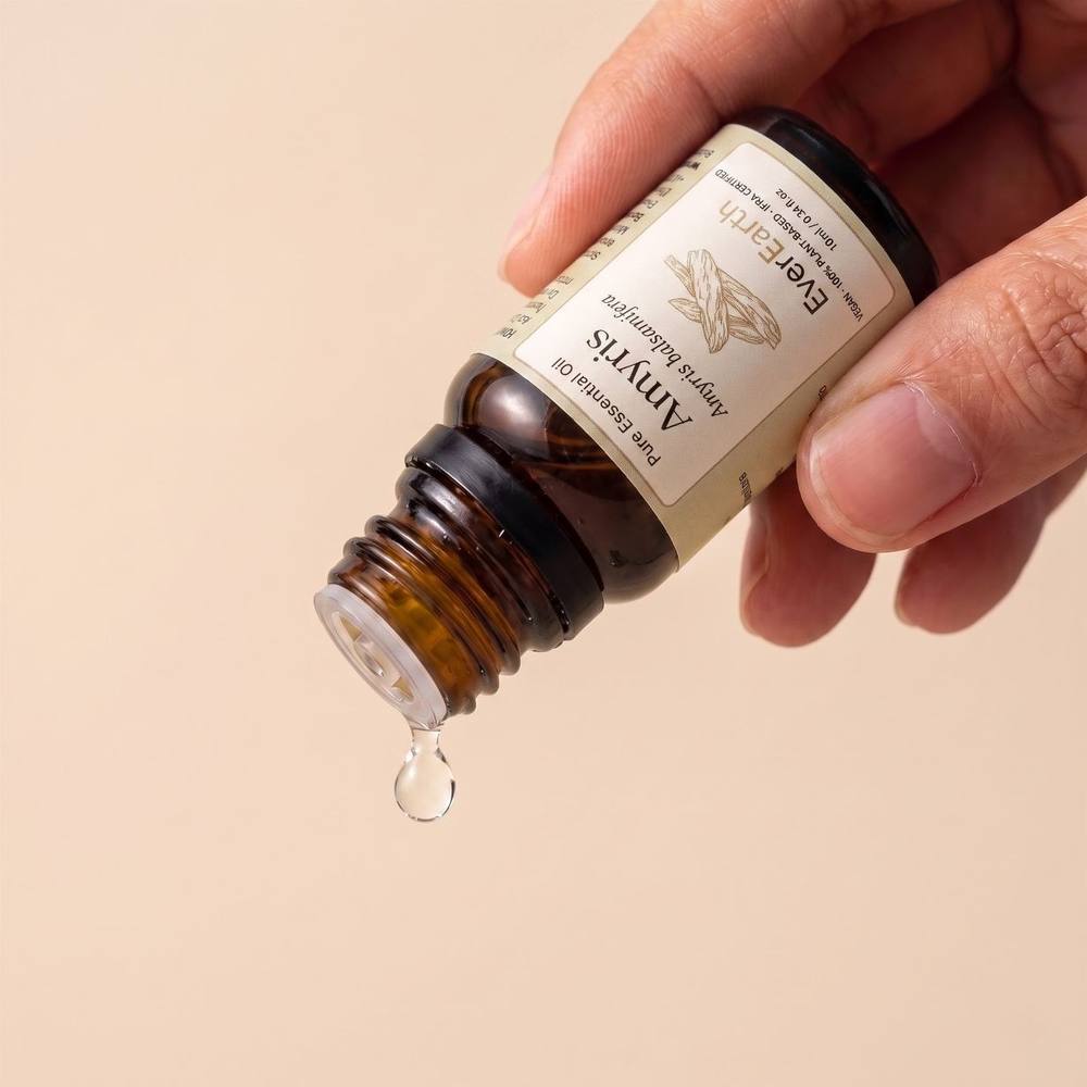 Hand dispensing a drop of EverEarth Amyris essential oil from the amber glass bottle