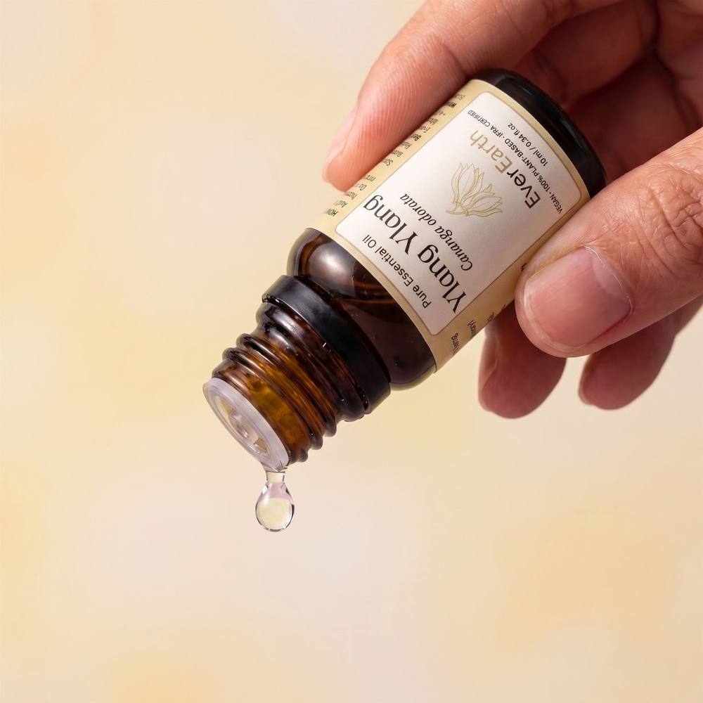 Hand tilting EverEarth Ylang Ylang essential oil bottle to release a single drop
