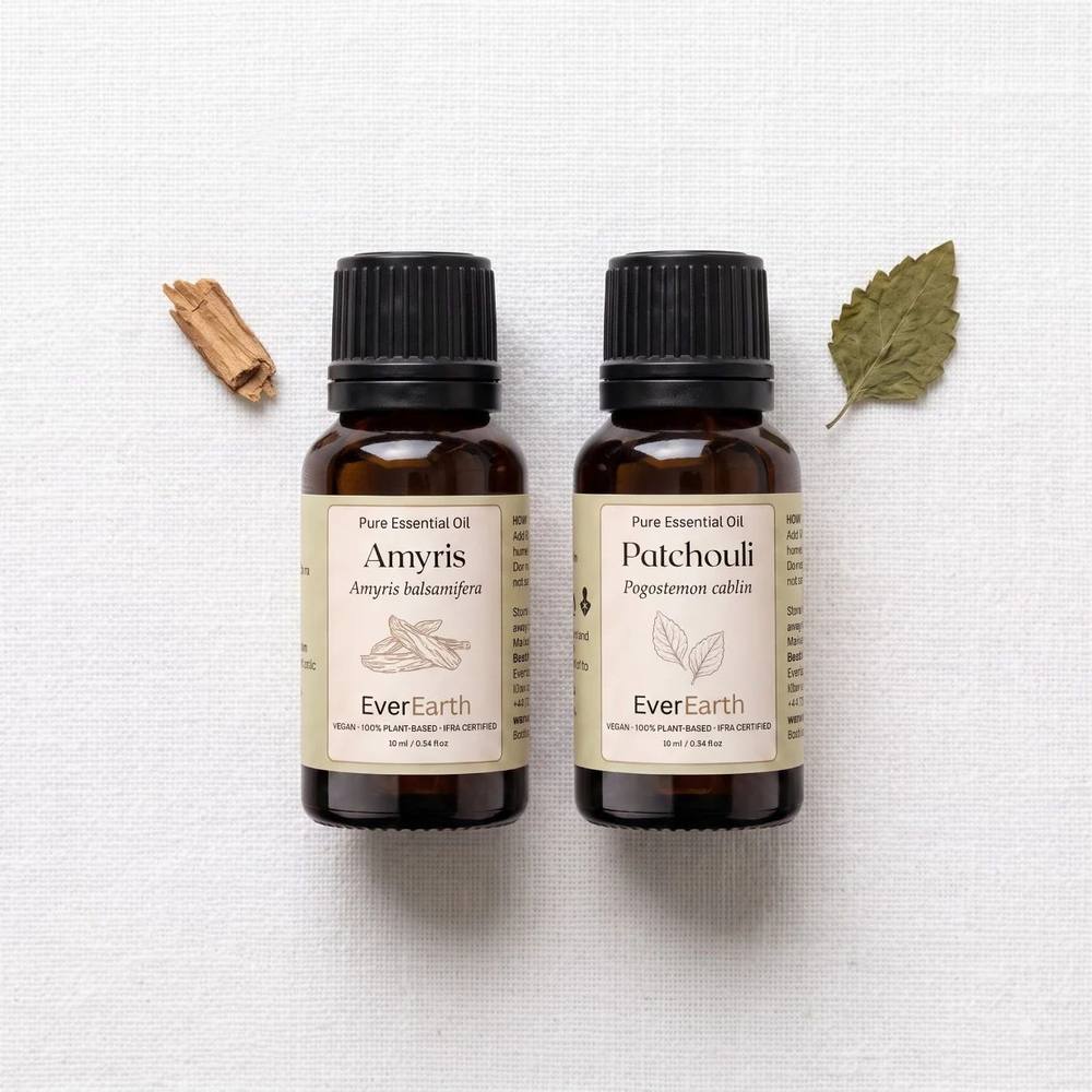 EverEarth Warm Duo flat lay with sandalwood chip and patchouli leaf on white linen